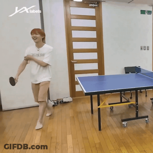 A Man Is Playing Ping Pong In A Room With A Sign That Says X Labels GIF