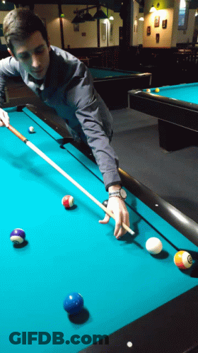 A Man Is Playing Pool With A Cue And Balls On The Table GIF