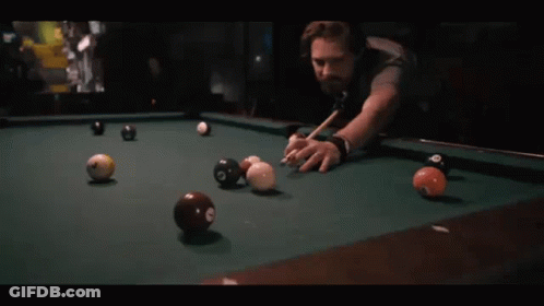 A Man Is Playing Pool With A Cue And Balls That Have The Number 8 On Them GIF