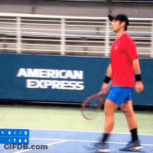 A Man Is Playing Tennis In Front Of A Banner That Says American Express GIF