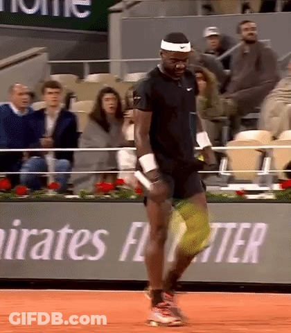 A Man Is Playing Tennis In Front Of A Banner That Says Emirates Fly Better GIF