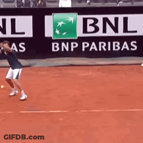 A Man Is Playing Tennis In Front Of A Bnp Paribas Banner GIF