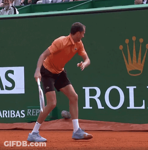 A Man Is Playing Tennis In Front Of A Rolex Ad GIF