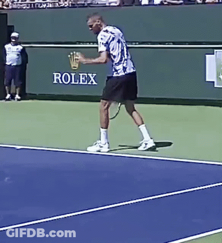 A Man Is Playing Tennis In Front Of A Rolex Banner GIF
