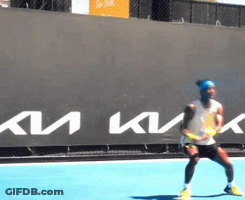 A Man Is Playing Tennis In Front Of A Sign That Says Km GIF