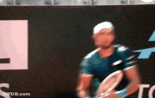 A Man Is Playing Tennis In Front Of A Top Sign GIF