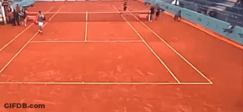 A Man Is Playing Tennis On A Clay Court . GIF