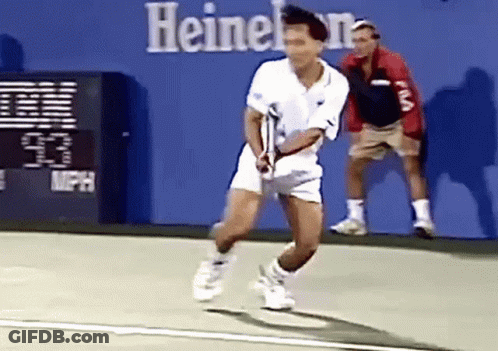 A Man Is Playing Tennis On A Court In Front Of A Sign That Says Heineken GIF