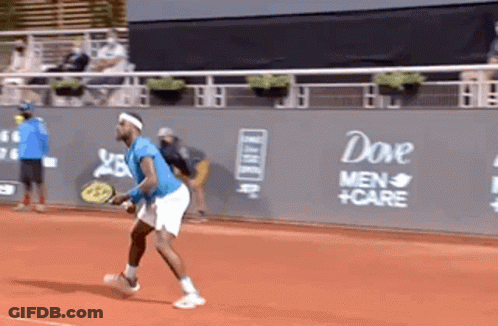 A Man Is Playing Tennis On A Court With A Dove Men 'S Care Advertisement On The Wall Behind Him GIF