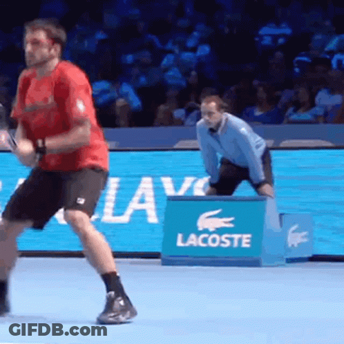 A Man Is Playing Tennis On A Court With A Lacoste Sign In The Background GIF