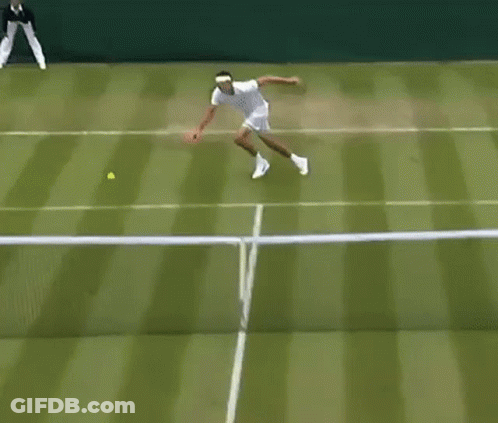 A Man Is Playing Tennis On A Tennis Court While A Referee Stands Behind Him . GIF