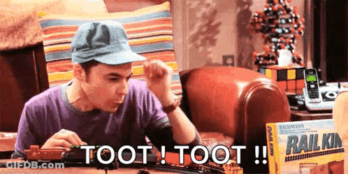 A Man Is Playing With A Train Set That Says Toot Toot On It GIF