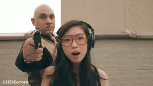A Man Is Pointing A Gun At A Girl Wearing Headphones GIF