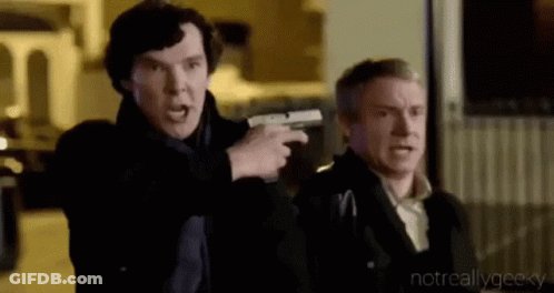 A Man Is Pointing A Gun At Another Man While They Are Standing Next To Each Other . GIF