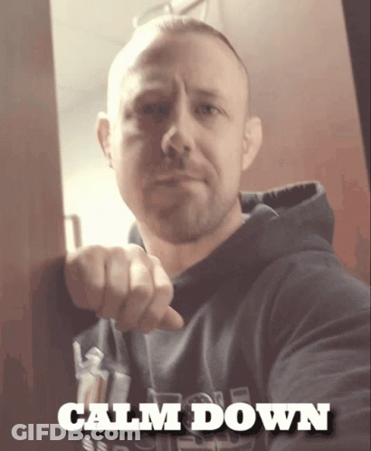 A Man Is Pointing At The Camera And The Words Calm Down Are Above Him GIF