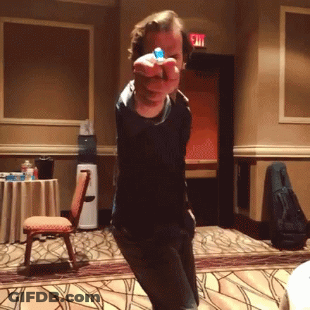 A Man Is Pointing At The Camera With A Blue Object In His Hand GIF