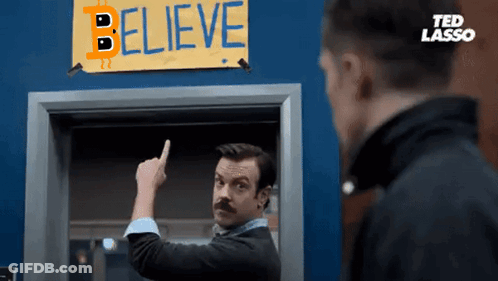 A Man Is Pointing To A Sign That Says Believe GIF