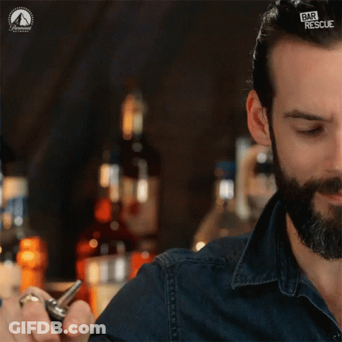 A Man Is Pouring Liquid Into A Glass With A Paramount Logo On The Bottom GIF