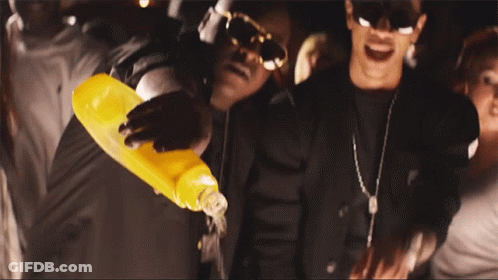 A Man Is Pouring Orange Juice Into Another Man 'S Mouth GIF