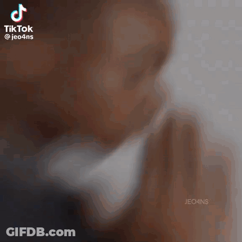 A Man Is Praying With His Hands Folded In Front Of His Face GIF