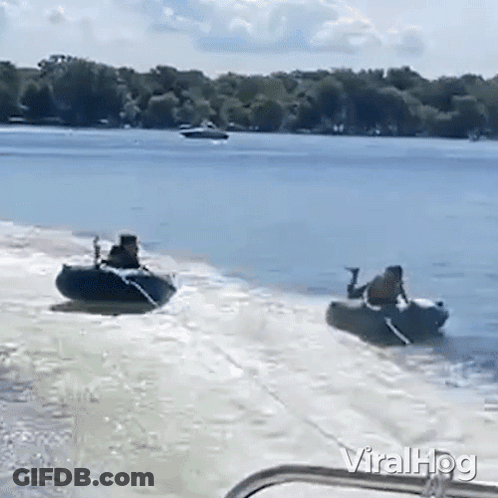 A Man Is Pulling A Boat With A Jet Ski Attached To It On A Lake . GIF