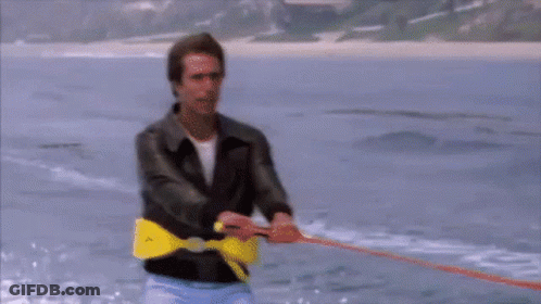 A Man Is Pulling A Rope In The Water With A Yellow Belt That Says T On It GIF