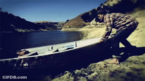 A Man Is Pushing A Boat Into The Water GIF