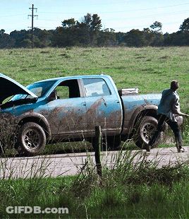 A Man Is Pushing A Muddy Truck That Has A Sticker On The Back That Says ' Emergency Assistance ' GIF