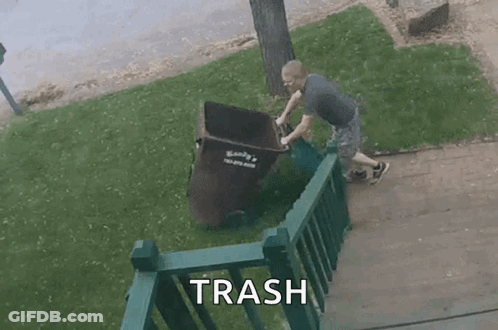 A Man Is Pushing A Trash Can Down A Sidewalk Next To A Railing . GIF