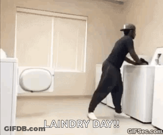 A Man Is Pushing A Washing Machine In A Laundry Room . GIF