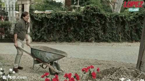 A Man Is Pushing A Wheelbarrow In A Garden With The Word Lopez On The Bottom GIF