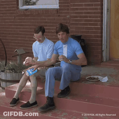 A Man Is Pushing Another Man On A Bicycle With A Bottle Of Soda On The Handlebars GIF
