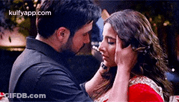 A Man Is Putting His Hand On A Woman 'S Forehead While They Are Kissing . GIF
