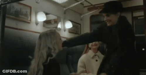 A Man Is Putting His Hand On A Woman 'S Head In A Train Car . GIF