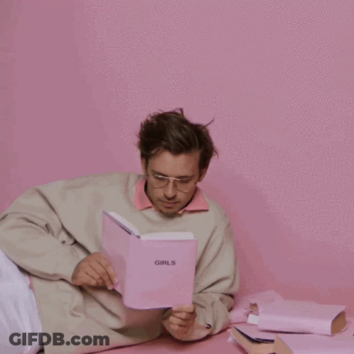 A Man Is Reading A Book Called Girls GIF