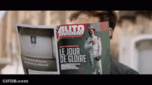 A Man Is Reading A Magazine That Says Le Jour De Gloire On The Front GIF