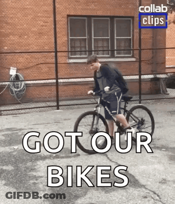 A Man Is Riding A Bike Down A Street With The Words `` Got Our Bikes '' Written On The Bottom . GIF