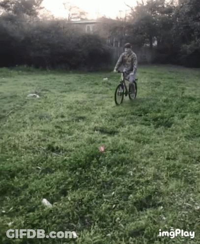 A Man Is Riding A Bike In A Grassy Field With The Hashtag Imgplay In The Lower Right Corner GIF