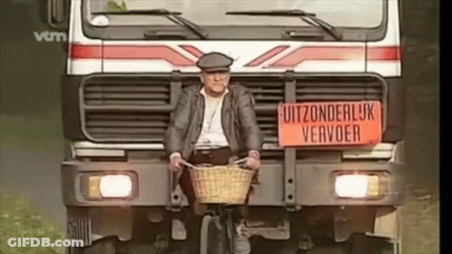 A Man Is Riding A Bike In Front Of A Truck With A Sign On It That Says Uitzonderlijk Vervoer GIF