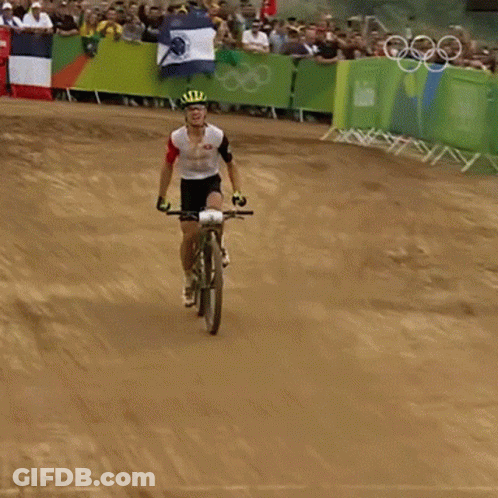 A Man Is Riding A Bike On A Dirt Track With A Crowd Behind Him GIF