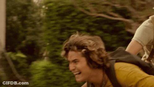 A Man Is Riding A Bike With A Backpack On His Back . GIF