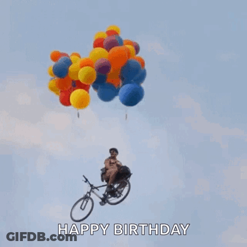 A Man Is Riding A Bike With Balloons Hanging From It In The Air . GIF