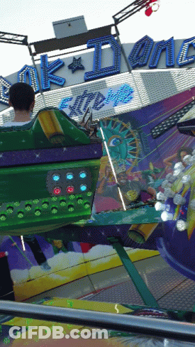 A Man Is Riding A Carnival Ride That Says ' Ak Dynamite Extreme ' On It GIF