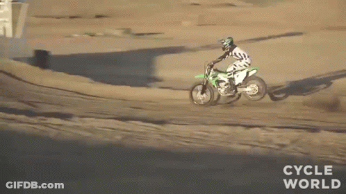 A Man Is Riding A Dirt Bike Down A Dirt Track . GIF