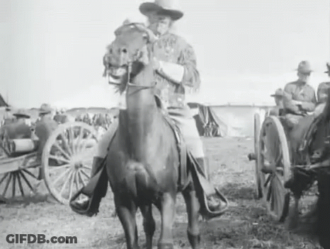 A Man Is Riding A Horse In A Field With A Wagon In The Background . GIF