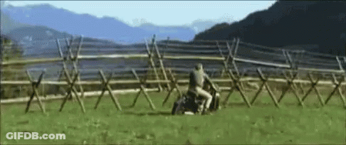 A Man Is Riding A Horse In A Field With Mountains In The Background GIF