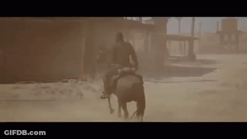 A Man Is Riding A Horse Through A Sandstorm In The Desert . GIF