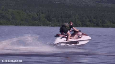 A Man Is Riding A Jet Ski In A Lake GIF