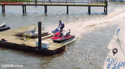 A Man Is Riding A Jet Ski In The Water Near A Dock GIF