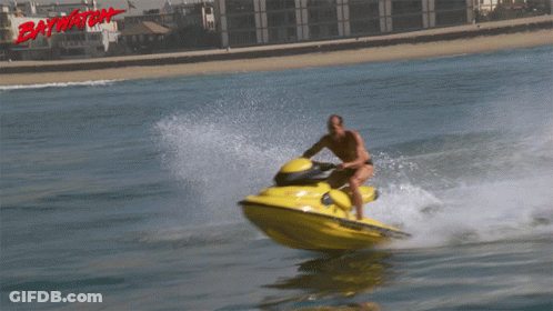 A Man Is Riding A Jet Ski With The Word Baywatch On The Bottom Right GIF